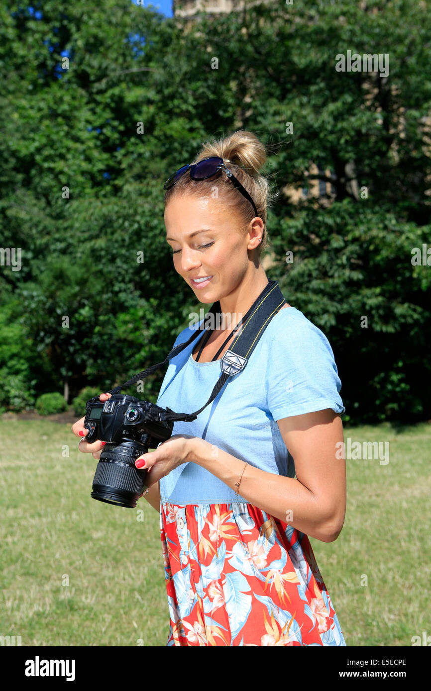 Eine junge Frau, die mit ihrer digitalen Kamera an einem sonnigen Tag Stockfoto