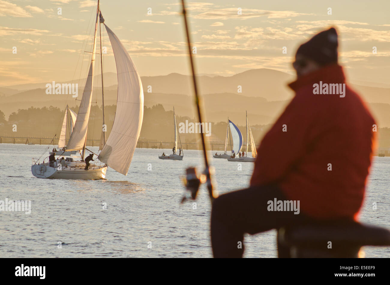 Segelboote und Angler bei Sonnenuntergang am Santander Bucht. Stockfoto