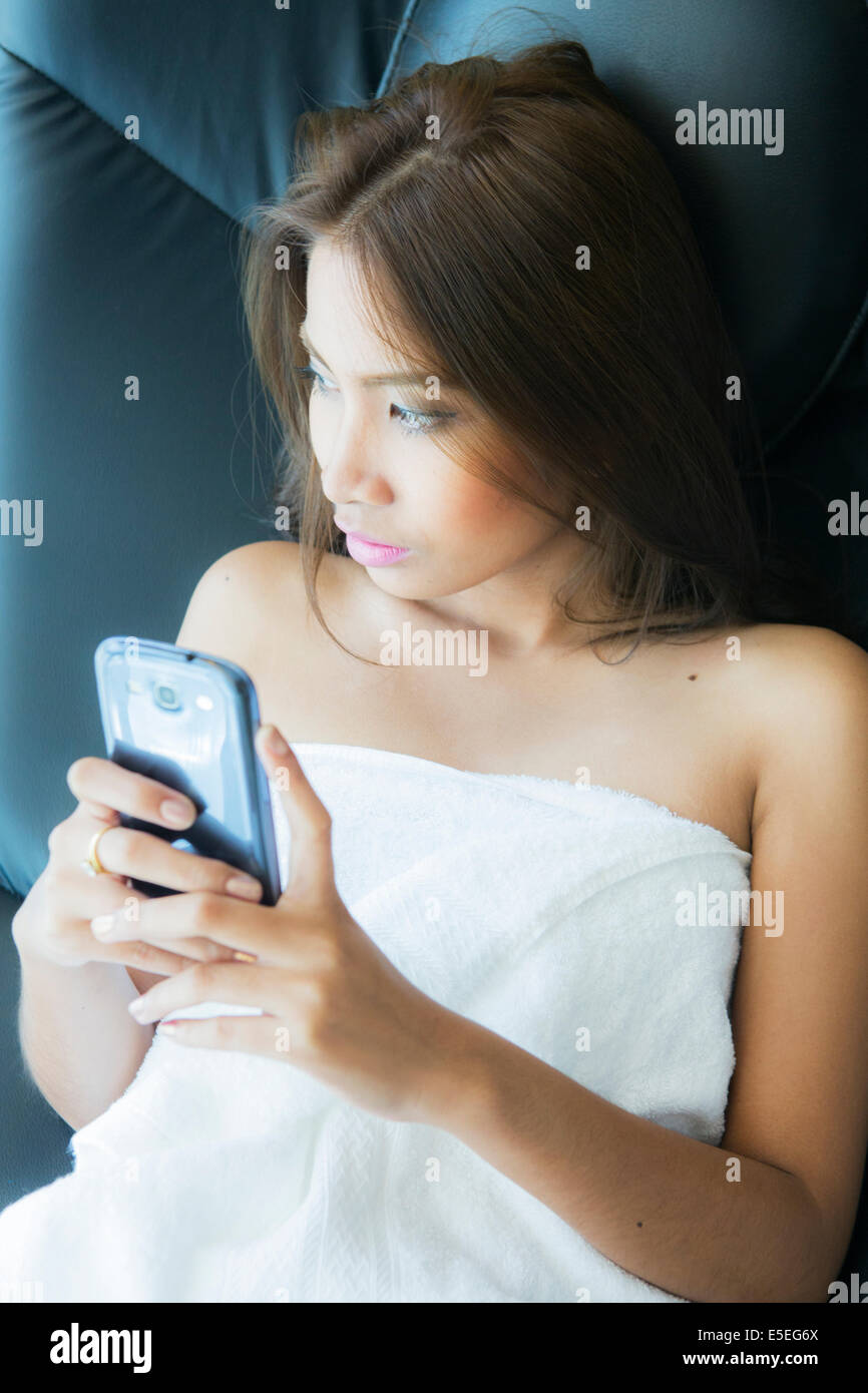 Eine junge asiatische Frau, die mit ihrem Tablet beim Entspannen zu Hause Stockfoto