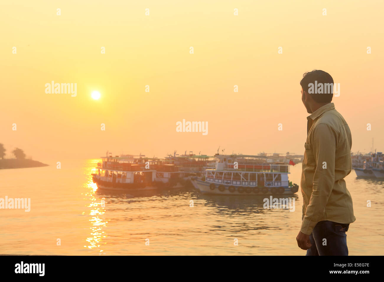 Ein indischer Mann, Blick auf den Sonnenaufgang von den Docks in Mumbai, Indien Stockfoto