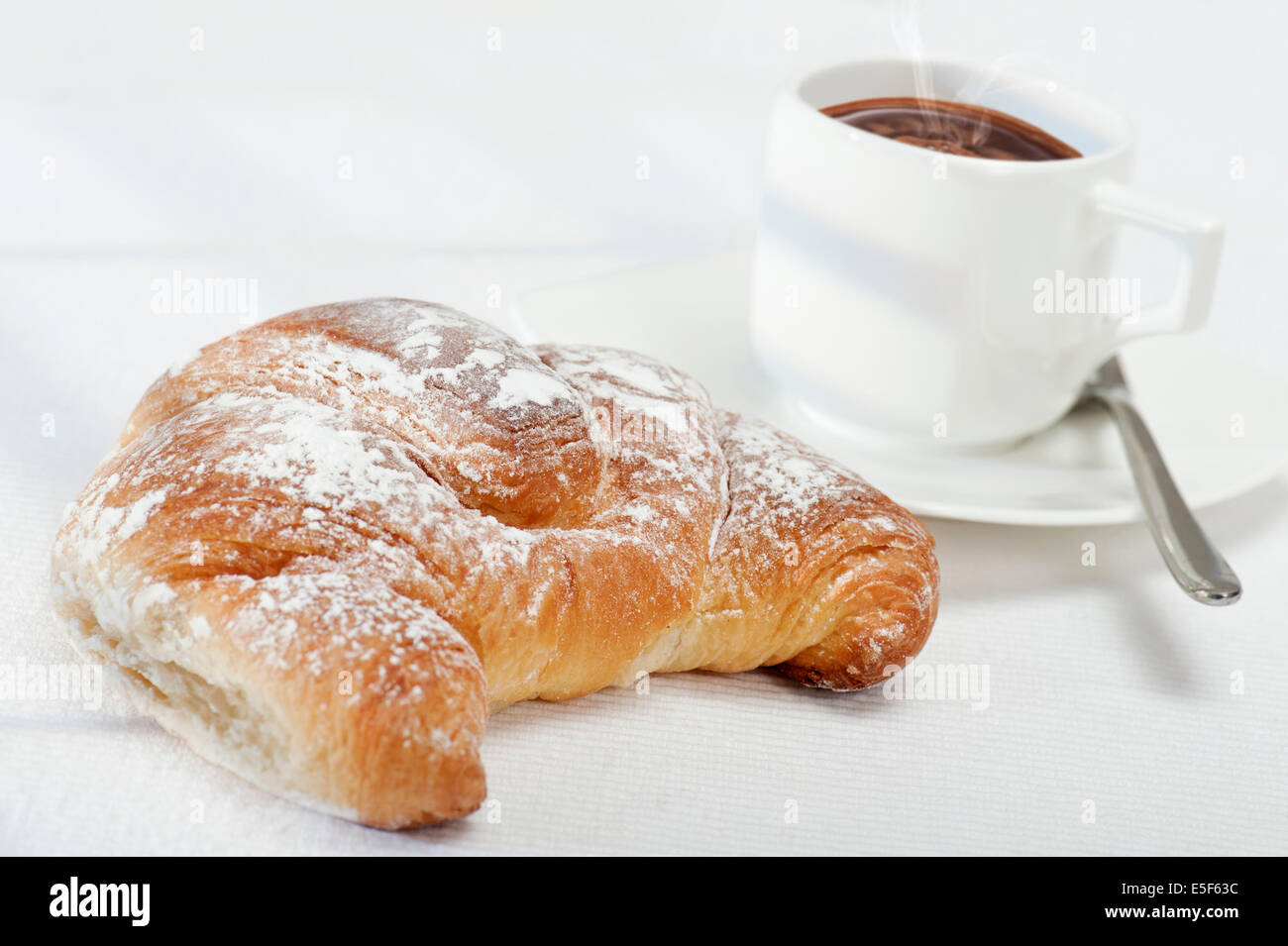 frische Brötchen Croissants mit Kaffee auf weiße Tischdecke mit Sonnenlicht Stockfoto