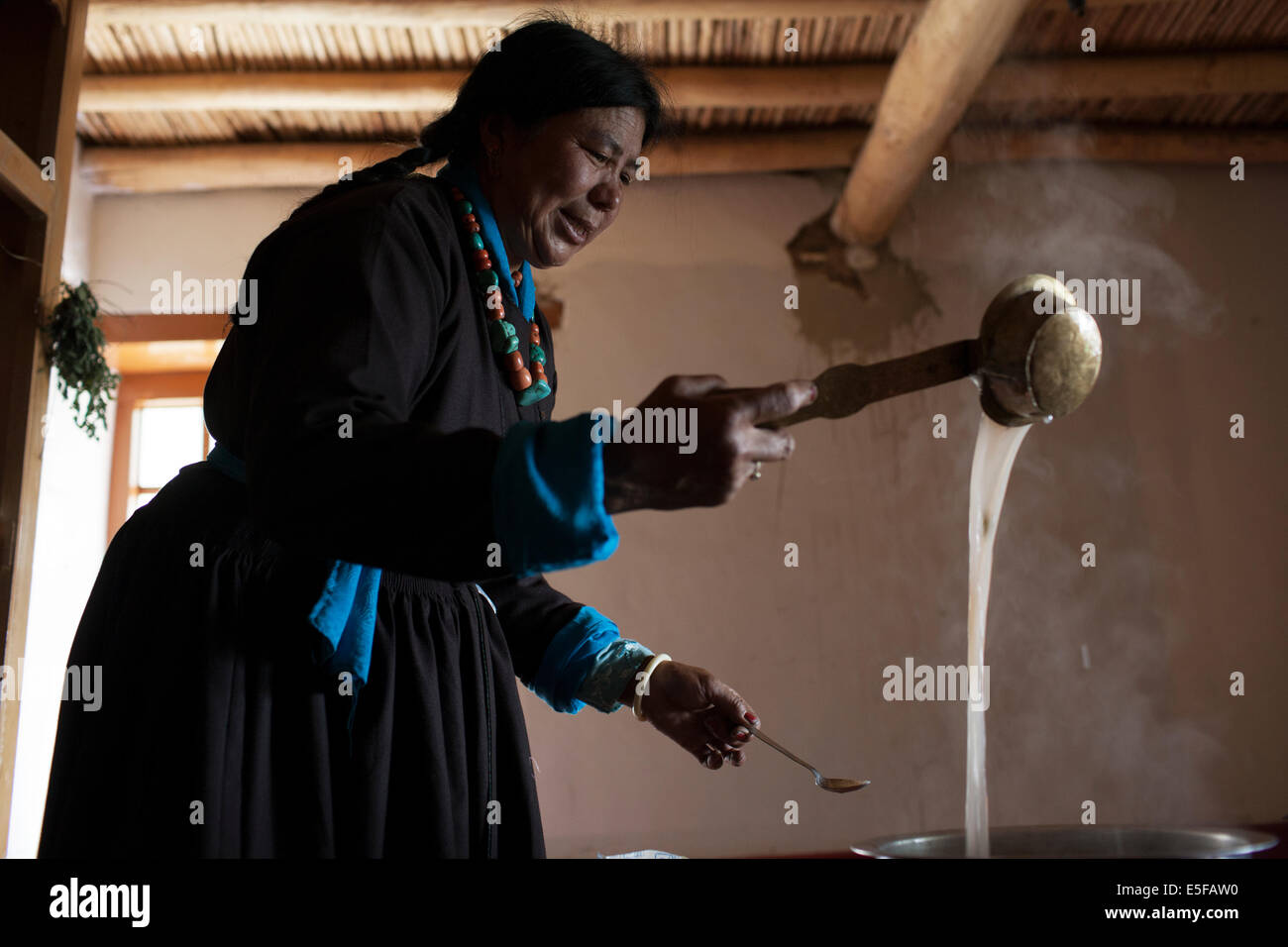 Eine Ladakhi Frauen in traditioneller Tracht machen tibetischen Buttertee. Stockfoto