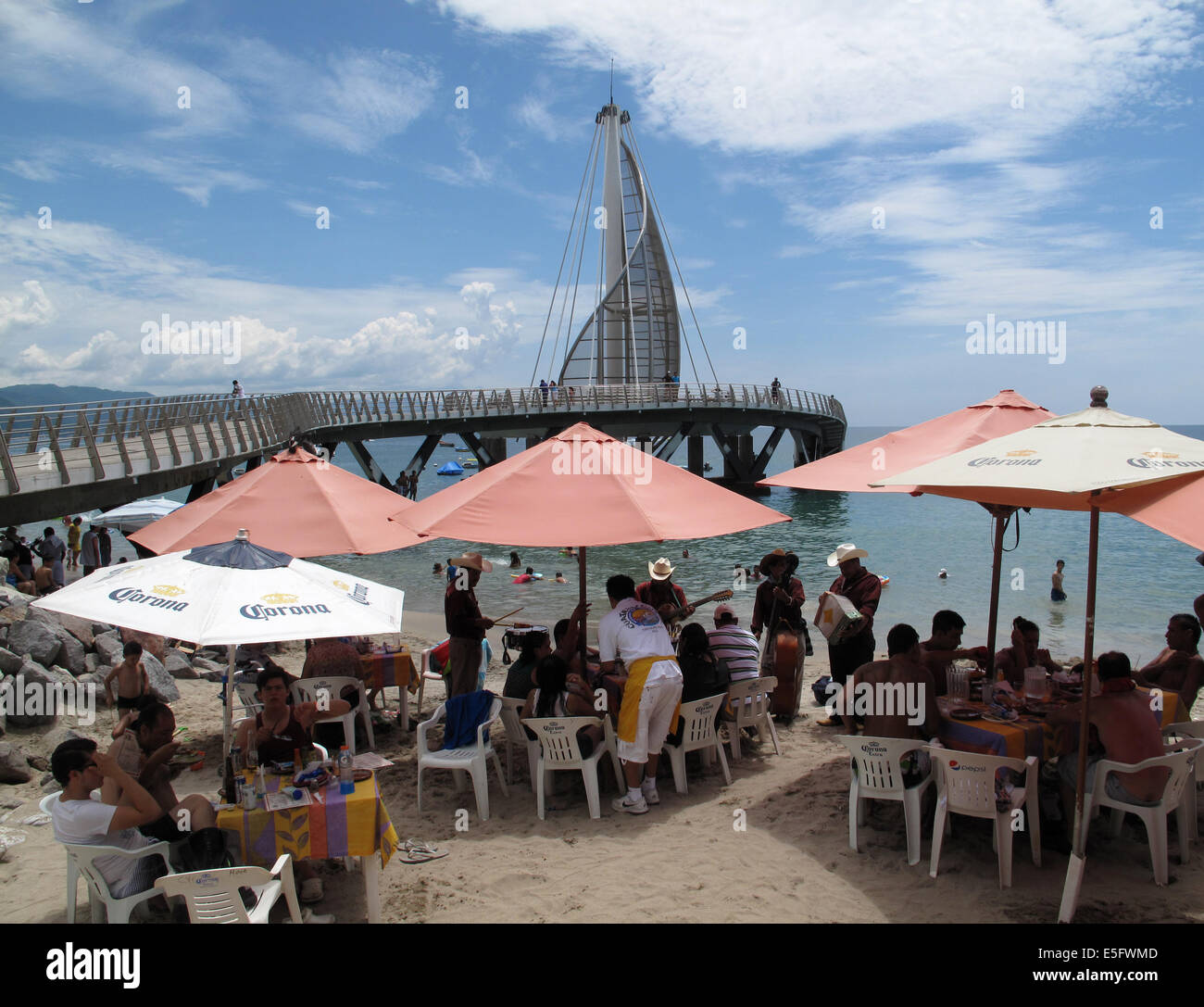 Menschen sitzen und Essen unter Sonnenschirmen neben Los Muertos Beach Pier, Puerto Vallarta, Mexiko. Stockfoto