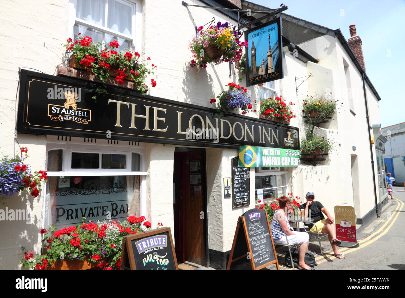 Eine Cornish "Pub mit hängenden Körbe, roten Blüten und ein 'London Inn'-Zeichen. Stockfoto