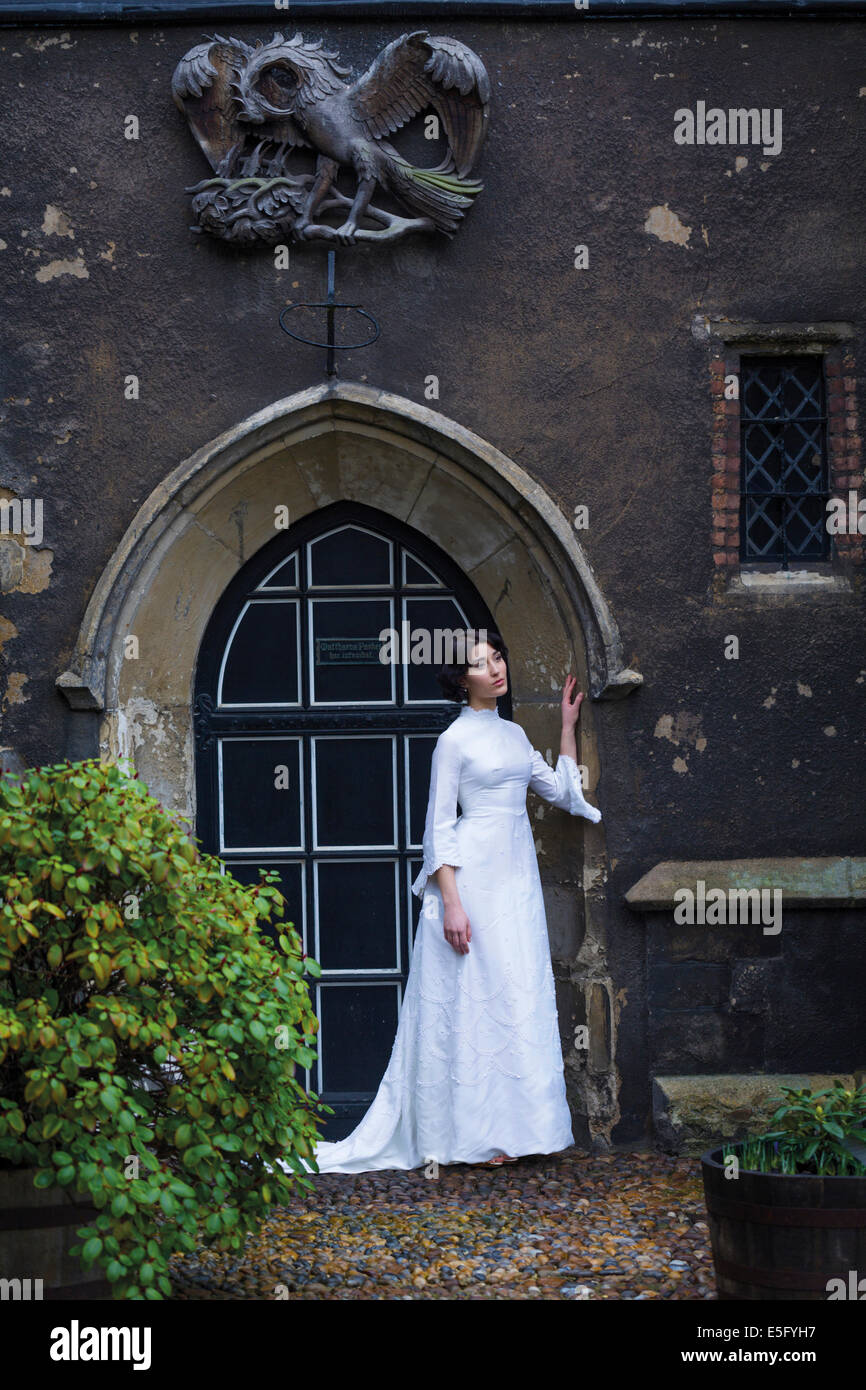 Eine einsame Braut in einem Hochzeitskleid, die am Eingang einer Kirche steht Stockfoto