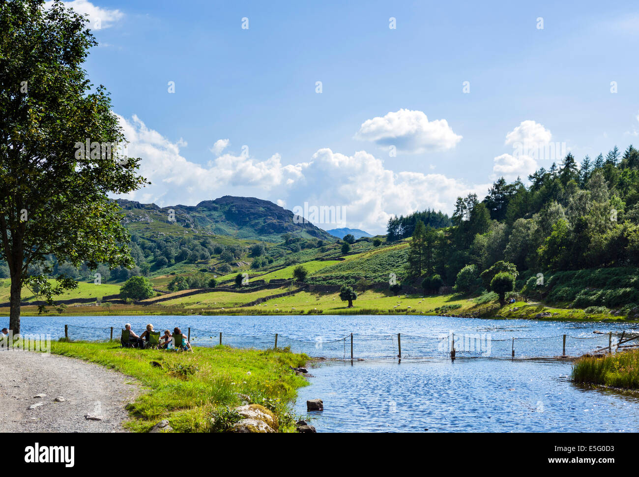 Menschen picknicken an der Seite des Watendlath Beck, Watendlath Tarn, Borrowdale, Lake District, Cumbria, UK Stockfoto