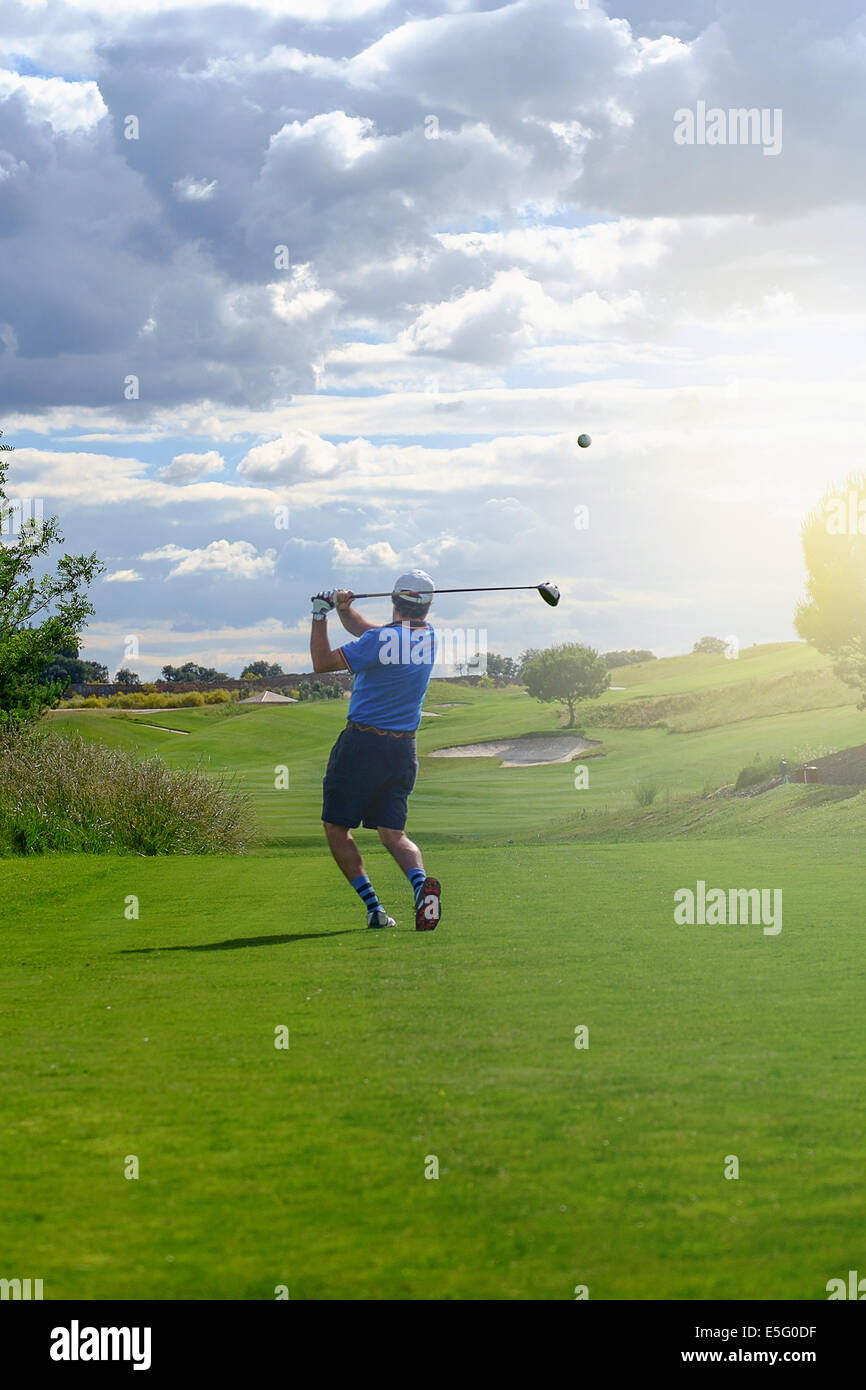 Männliche Golfspieler Abschlag Golfball vom Abschlag in den Sonnenuntergang Stockfoto
