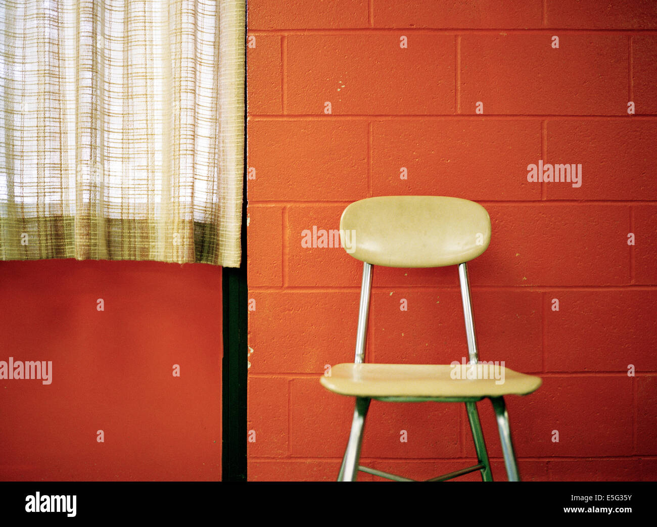Stuhl stehend durch rote Wand Stockfoto