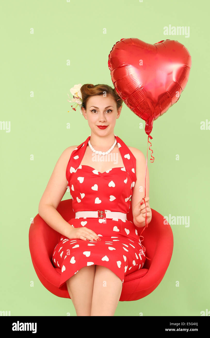 Frau im roten Kleid hält herzförmige Ballons Stockfoto