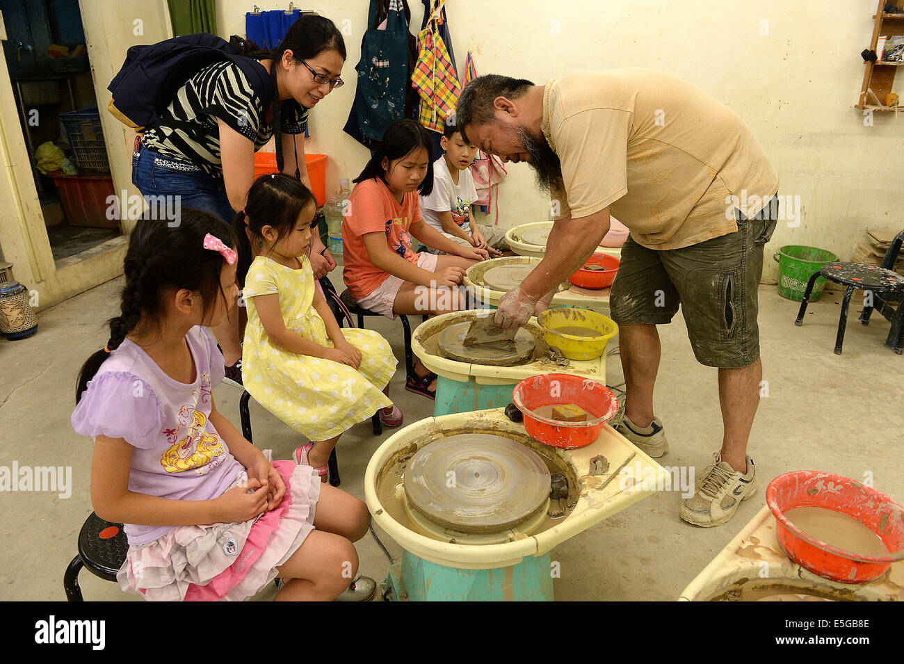 (140731)--XINBEI, 31. Juli 2014 (Xinhua)--Kinder lernen Keramikproduktion von einem Lehrer in Yingge Straße von Xinbei City, Südost-China Taiwan, 30. Juli 2014. Die Geschichte der Keramikproduktion in Yingge Straße begann vor etwa 200 Jahren, verschiedene Arten von Feinkeramik produziert hier ziehen viele Touristen an.  (Xinhua / He Junchang) (Whw) Stockfoto