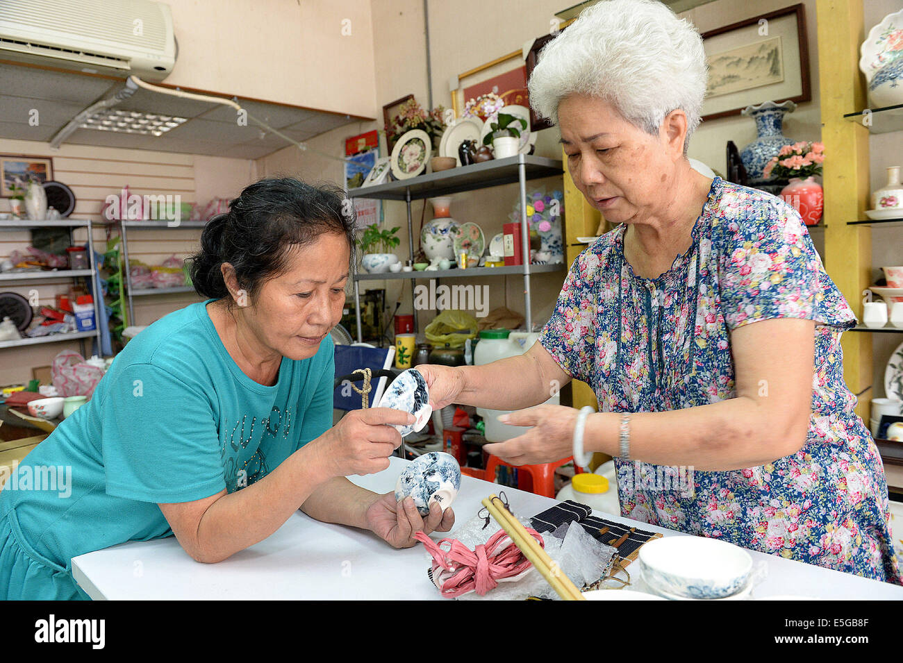 (140731)--XINBEI, 31. Juli 2014 (Xinhua)--eine Frau (L) lernt Keramikmalerei von einem Lehrer in Yingge Straße von Xinbei City, Südost-China Taiwan, 30. Juli 2014. Die Geschichte der Keramikproduktion in Yingge Straße begann vor etwa 200 Jahren, verschiedene Arten von Feinkeramik produziert hier ziehen viele Touristen an.  (Xinhua / He Junchang) (Whw) Stockfoto
