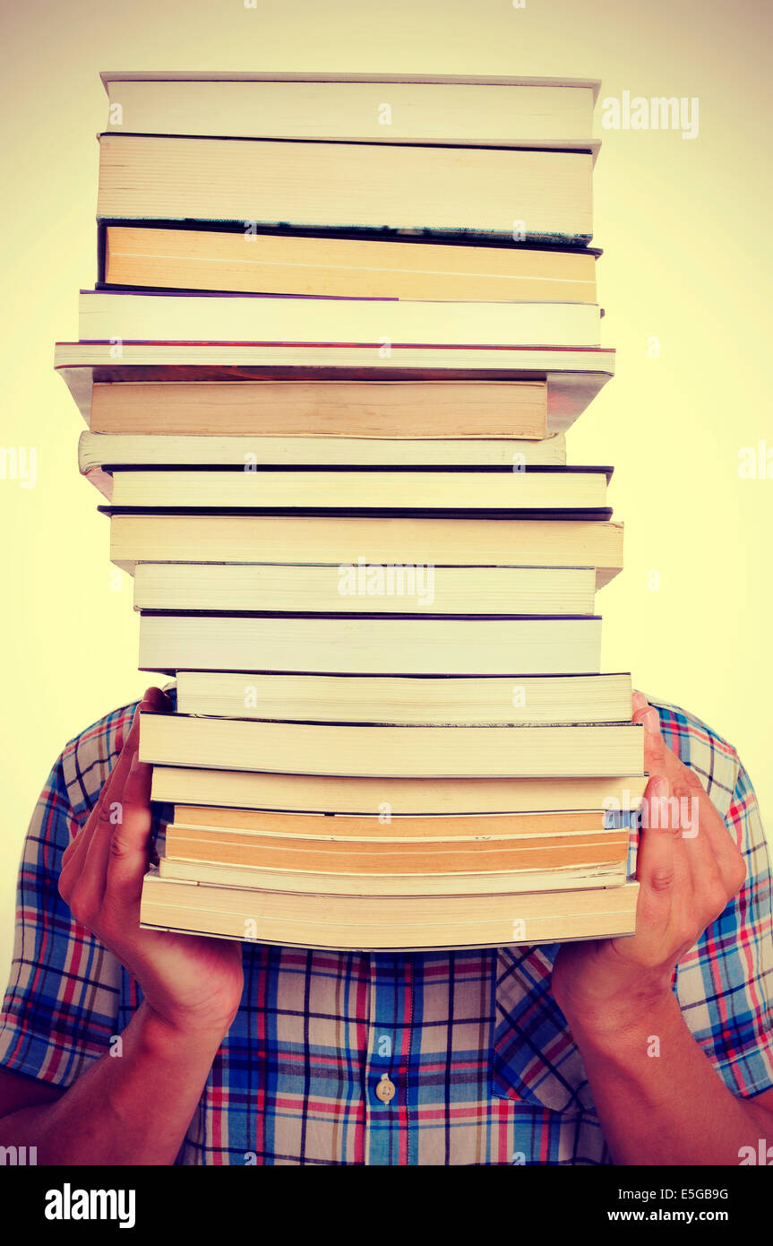 ein junger Mann hält einen Stapel Bücher vor seinem Gesicht, mit einem Filtereffekt Stockfoto