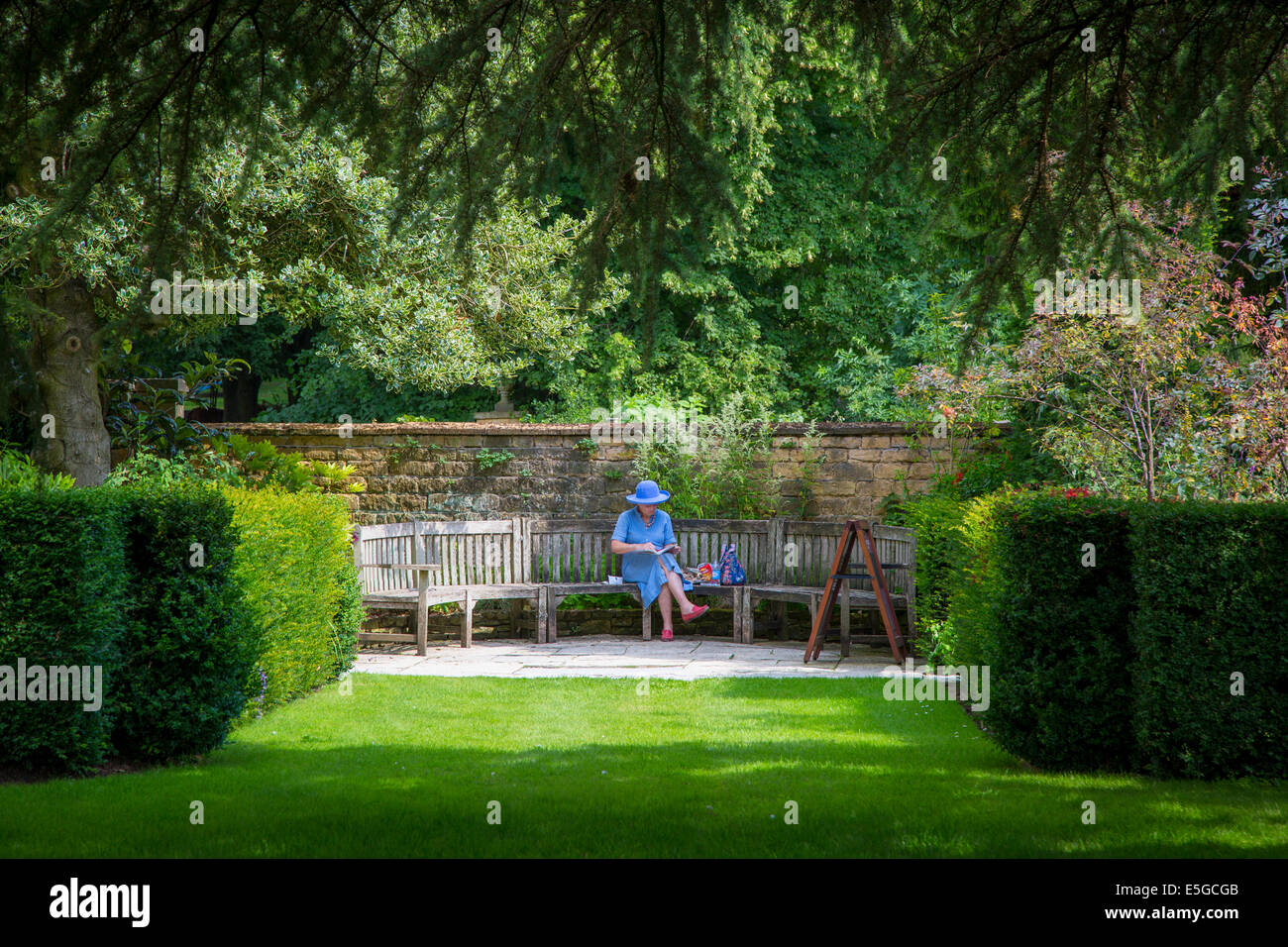 Frau Lesebuch in Hidcote Garten in der Nähe von Chipping-Campden, Cotswolds, Gloucestershire, England Stockfoto