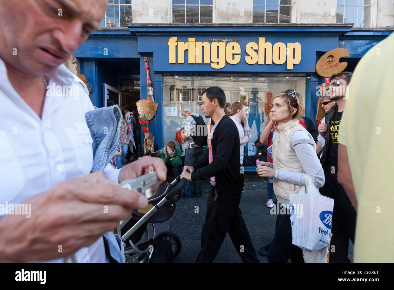 Festival-Besucher passieren das Edinburgh Fringe-Shop in der Stadt High Street. Stockfoto