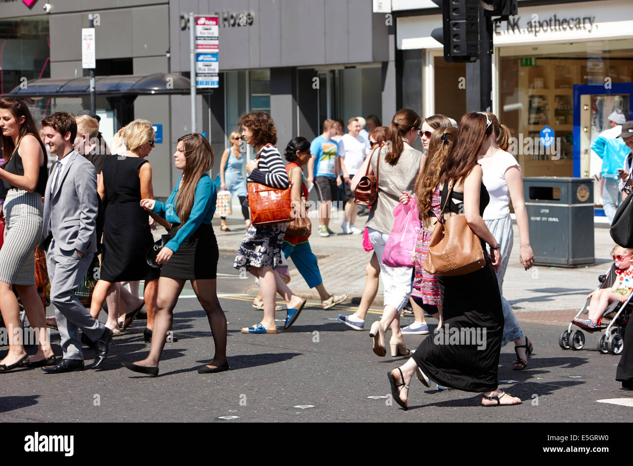 Menschen beim Überqueren der Straße auf einem Fußgängerüberweg zur Mittagszeit an anstrengenden Sommertag Belfast Stadtzentrum Stockfoto