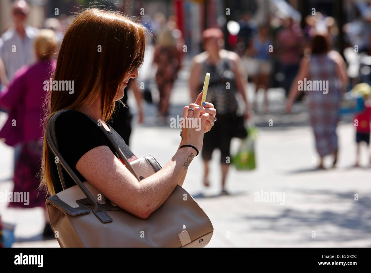 Frau mit Smartphone, ein Foto oder Text im Stadtzentrum von Belfast zu nehmen Stockfoto