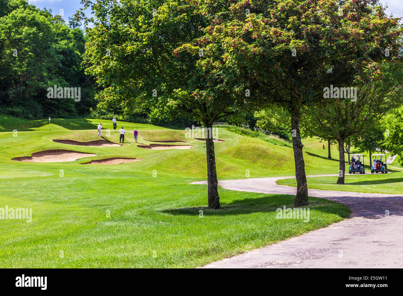 Vier männliche Golfer spielen auf einem Golfplatz in der Nähe von Bunkern. Stockfoto