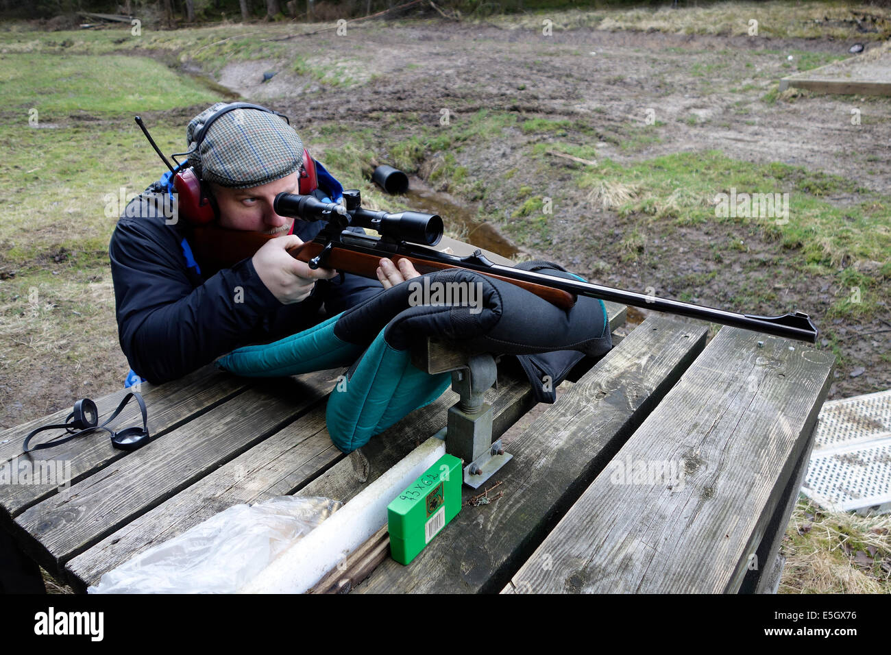 Jäger mit Jagdgewehr, ausgestattet mit einem Gültigkeitsbereich soll ein Training Runden schießen. Stockfoto