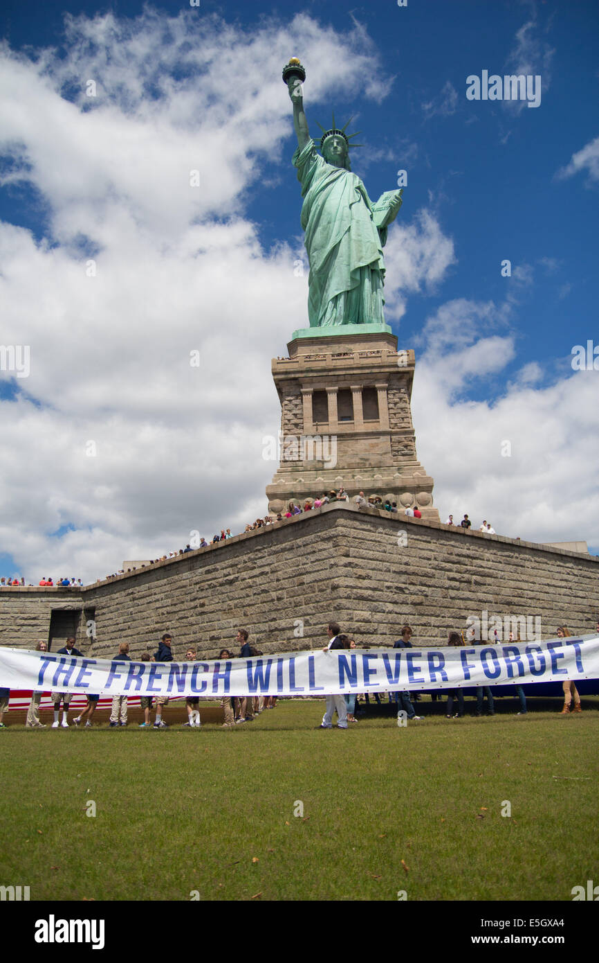 Führung mit der französischen werde nie vergessen, ein französischer gemeinnütziger Verein zu erhöhen einen Banner vor der Statue of Liberty Stockfoto