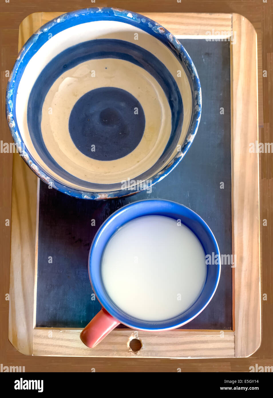 Schale und Tasse Milch auf dem Blackboard-Hintergrund Stockfoto