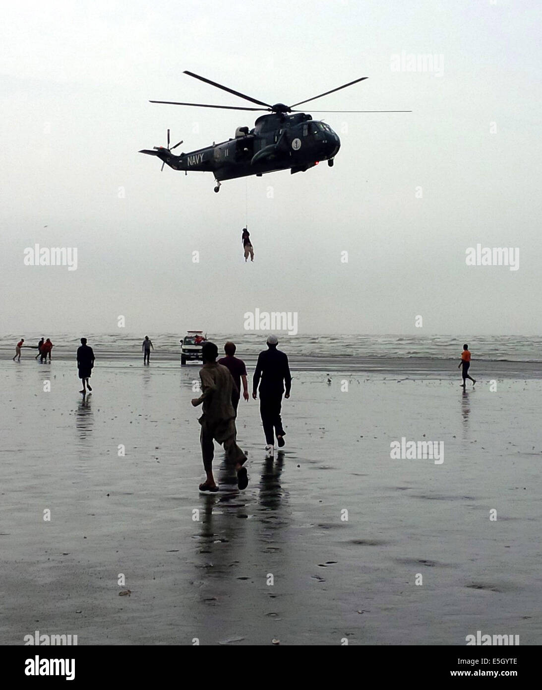 Karachi. 31. Juli 2014. Pakistan Marine Sea King Hubschrauber ist mit einem Froschmann, befestigt an einer Winde aus dem Flugzeug, die einen wiederhergestellten Körper ein ertrinkendes Opfer über Clifton Beach im südlichen Hafenstadt pakistanischen Stadt Karachi am 31. Juli 2014 transportiert gesehen. Mindestens 19 Leichen der Opfer wurden wiederhergestellt, nachdem sie beim Baden im Meer in der Nähe von Pakistans südlichen Hafen Stadt Karachi am Mittwoch, ertrunken war, berichteten lokale Medien. © Arshad/Xinhua/Alamy Live-Nachrichten Stockfoto