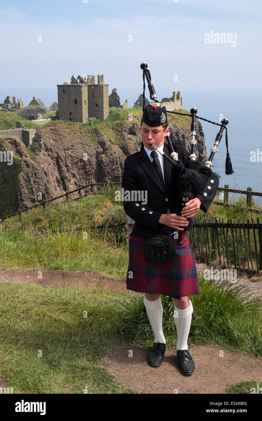 Piper spielt Dudelsäcke im traditionellen schottischen Kilt im Dunnottar Castle in Aberdeenshire, Schottland, Großbritannien Stockfoto