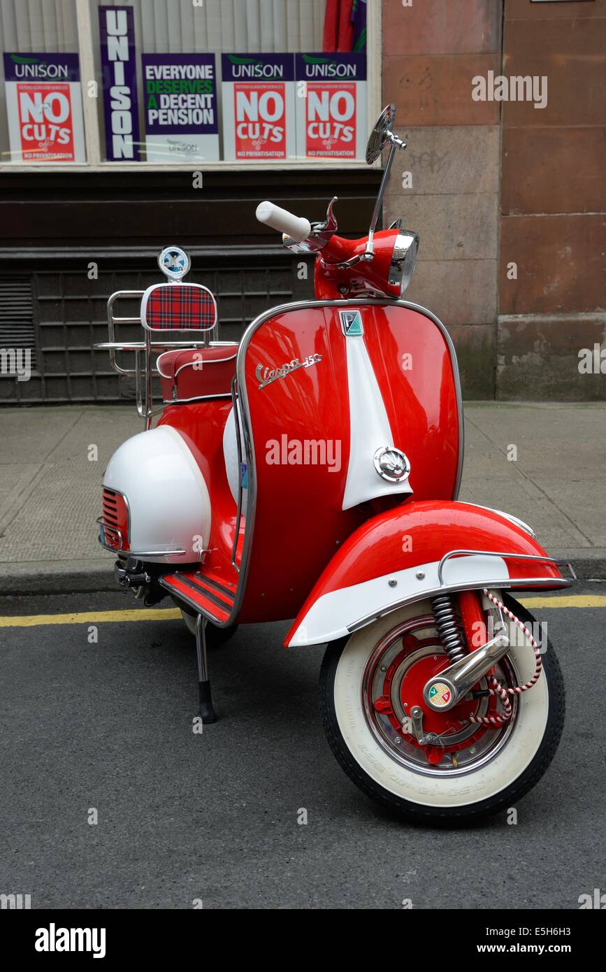 Ein Roller Piaggio Vespa 150 roter und weißer geparkt auf eine einzelne gelbe Linie in Glasgow, Scotland, UK Stockfoto