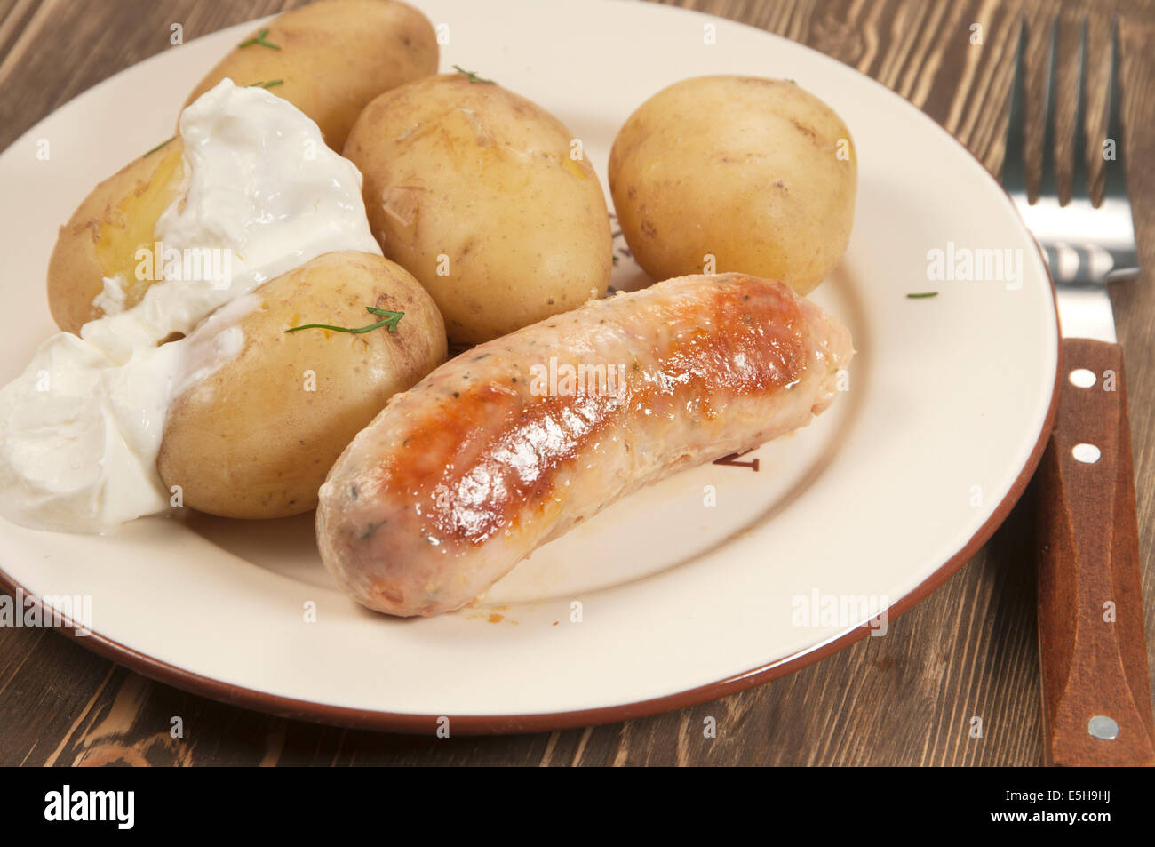 Junge Kartoffeln mit Sauerrahm und Wurst Stockfotografie - Alamy