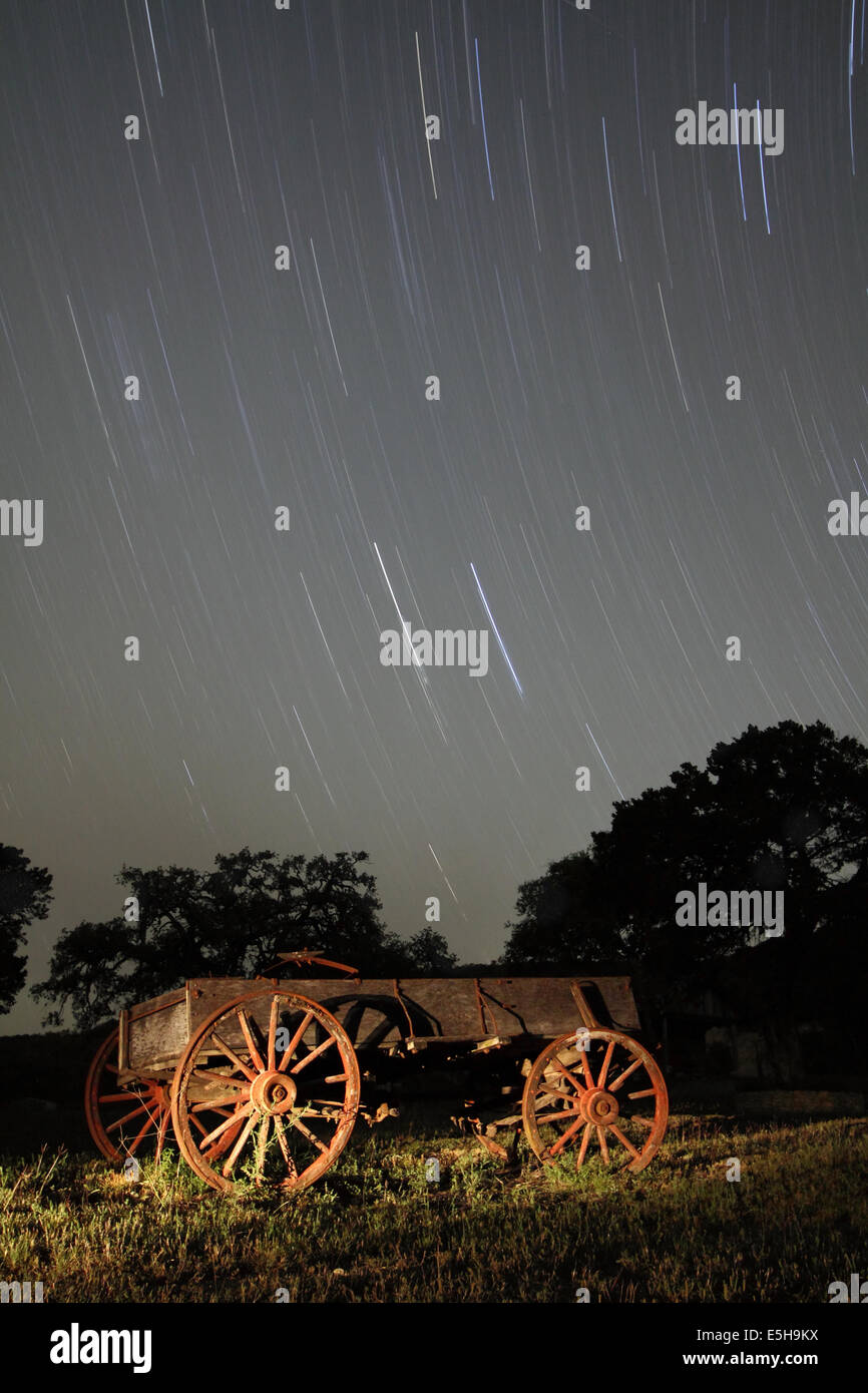 Eine alte Holzwagen mit rostigen Rädern ruht unter den Sternen der Nacht in einem Bauernhof-Feld in Texas, USA. Stockfoto