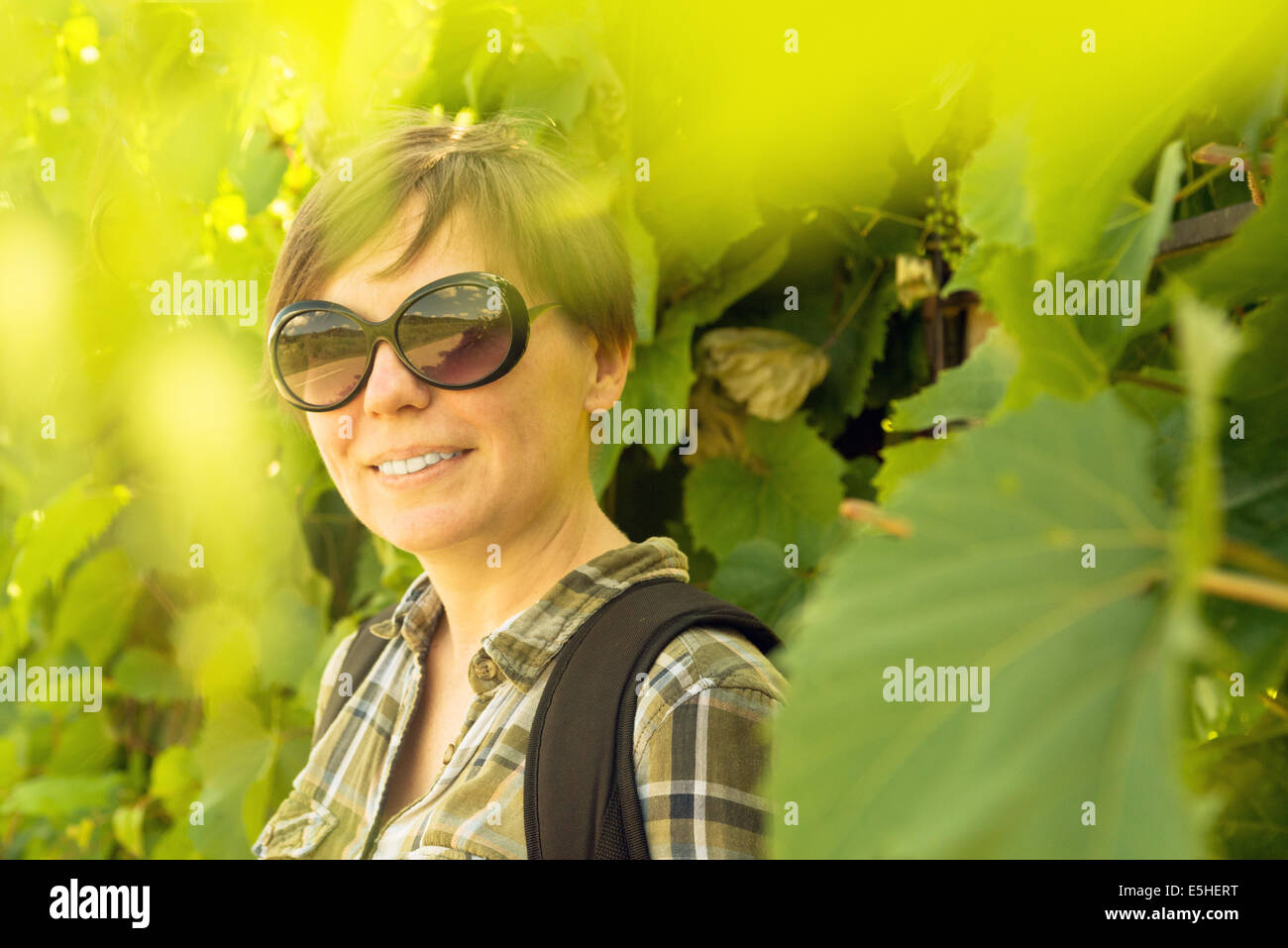 Lächelnde junge Frau im Weinberg. Lässige glücklich im freien Frauenporträt. Stockfoto