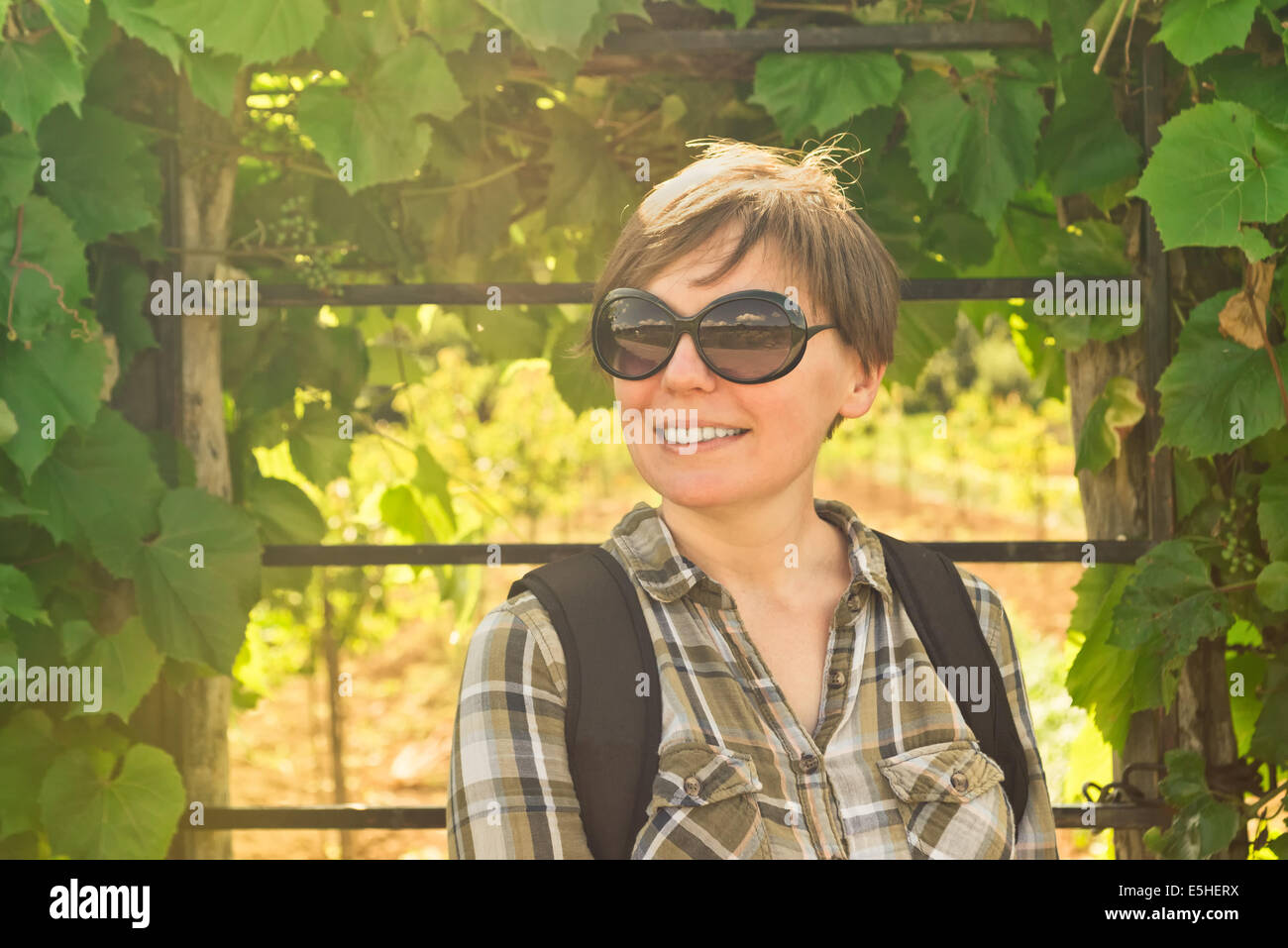 Lächelnde junge Frau im Weinberg. Lässige glücklich im freien Frauenporträt. Stockfoto
