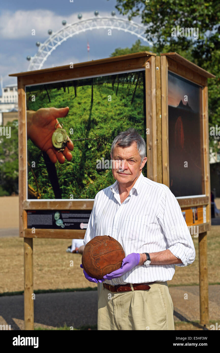 London, UK. 1. August 2014. Fotograf Mike St. Maur Sheil auf Felder der Schlacht Ländereien des Friedens 14-18 Ausstellung gesponsert The Royal British Legion im Freien in St. James' Park, London, England. Die Ausstellung erinnert an die Hundertjahrfeier des ersten Weltkriegs und beginnt am 4. August, zum 100. Geburtstag des ersten Weltkrieges in Großbritannien. Es läuft bis November.  Mike hält die Loos-Fußball, die die London Irish Rifles über No Mans Land am 25. September 1915 begann, wie sie die deutschen Stellungen in der Stadt von Loos angegriffen. Bildnachweis: Paul Brown/Alamy Live-Nachrichten Stockfoto