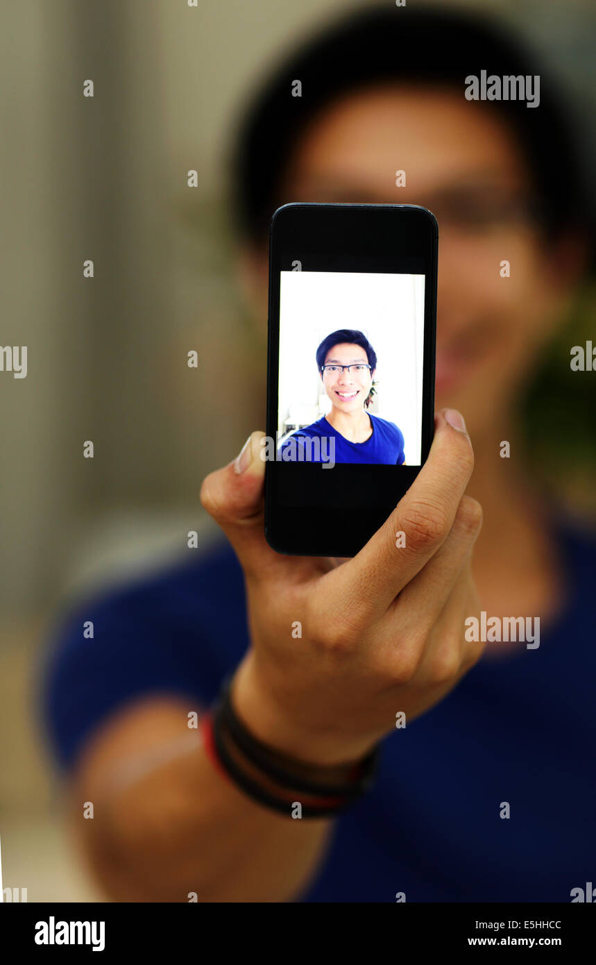 Glücklich asiatischer Mann selbst fotografieren mit Smartphone-Kamera. Smartphone im Fokus Stockfoto