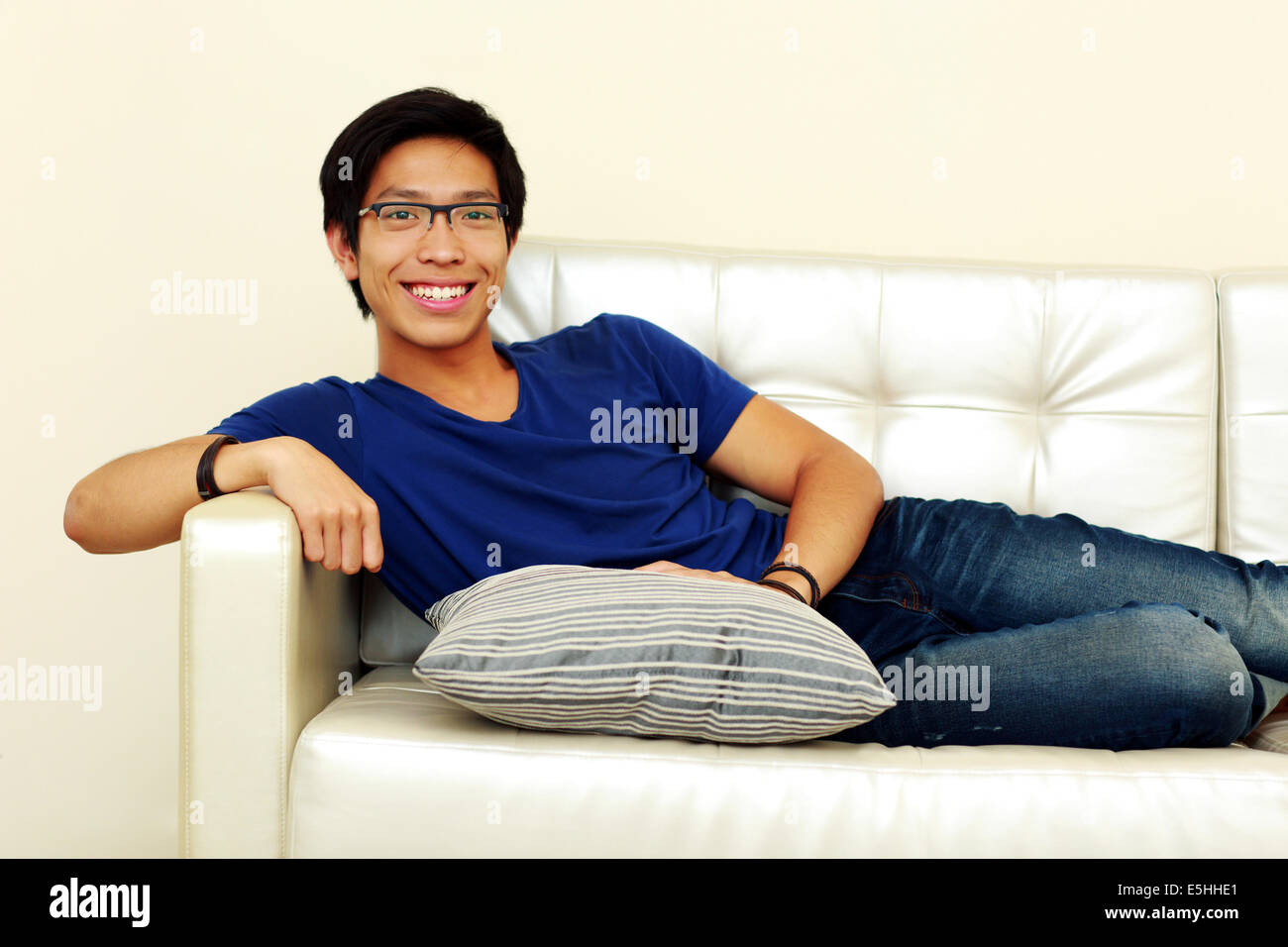 Lächelnder asiatischen Mann zu Hause auf dem Sofa entspannen Stockfoto