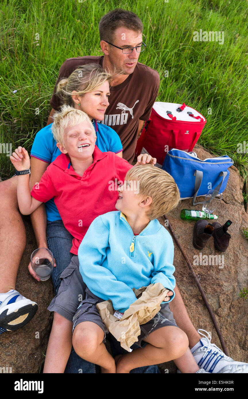 Vierköpfige Familie ruht für Picknick auf Felsen Stockfoto