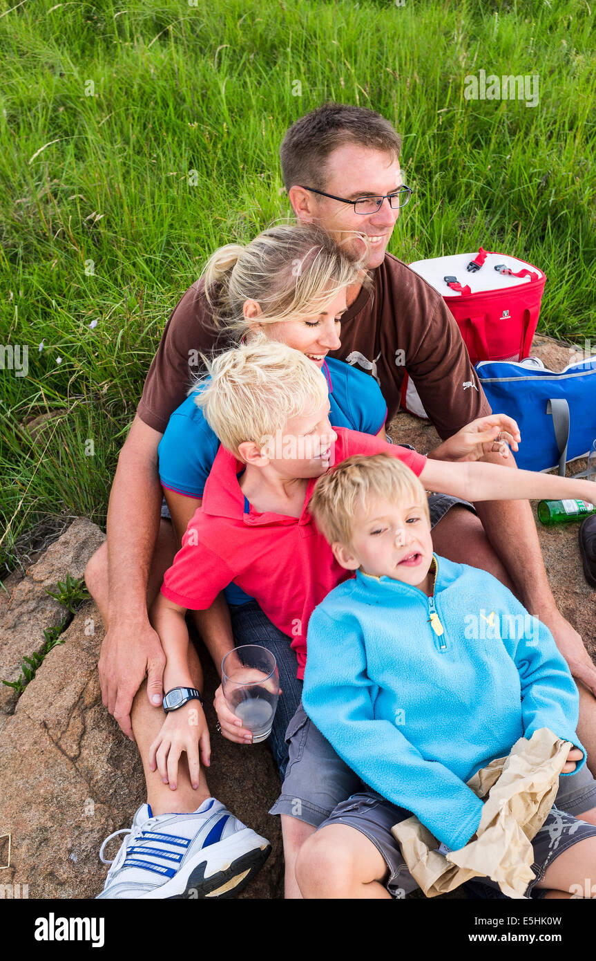 Vierköpfige Familie ruht für Picknick auf Felsen Stockfoto