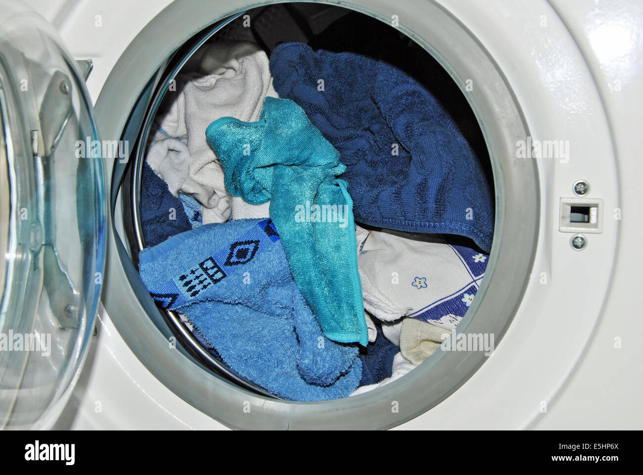 Nahaufnahme einer offenen Tür einer geladenen Waschmaschine mit Wäsche Stockfoto