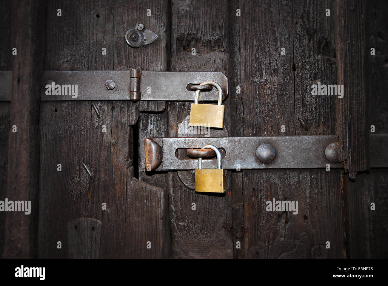 zwei goldene Sicherheitsschlösser mit Riegel auf eine alte, hölzerne Tür, Nahaufnahme Stockfoto