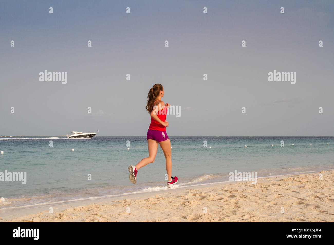 Junge gesunde Frau laufen am Strand in kurzen Hosen Stockfoto