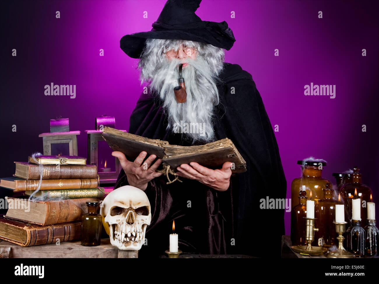 Alte Halloween Zauberer lesen ein Zauberbuch in seiner Küche Stockfoto
