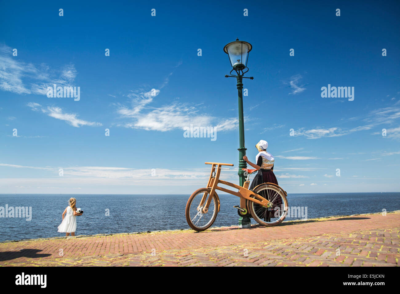 Niederlande, Urk, Ast Bike. Das Dutch Design aus Holz-Bike ist eine Schöpfung von Jan Gunneweg. Mädchen in Tracht Sonntag Stockfoto