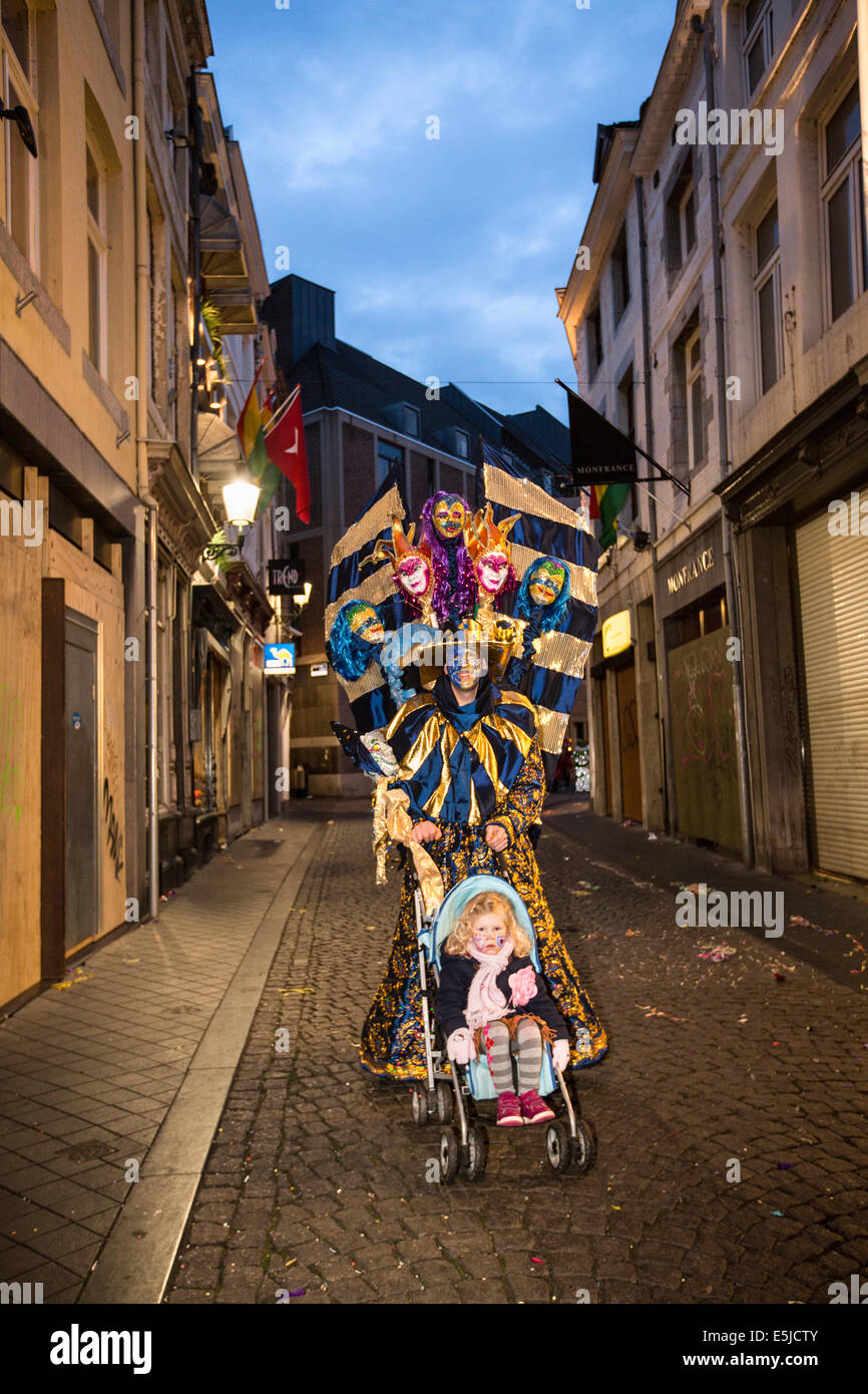 Niederlande, Maastricht, Karneval. Kostümierter Mann geht mit seiner Tochter in Baby Auto. Twilight Stockfoto