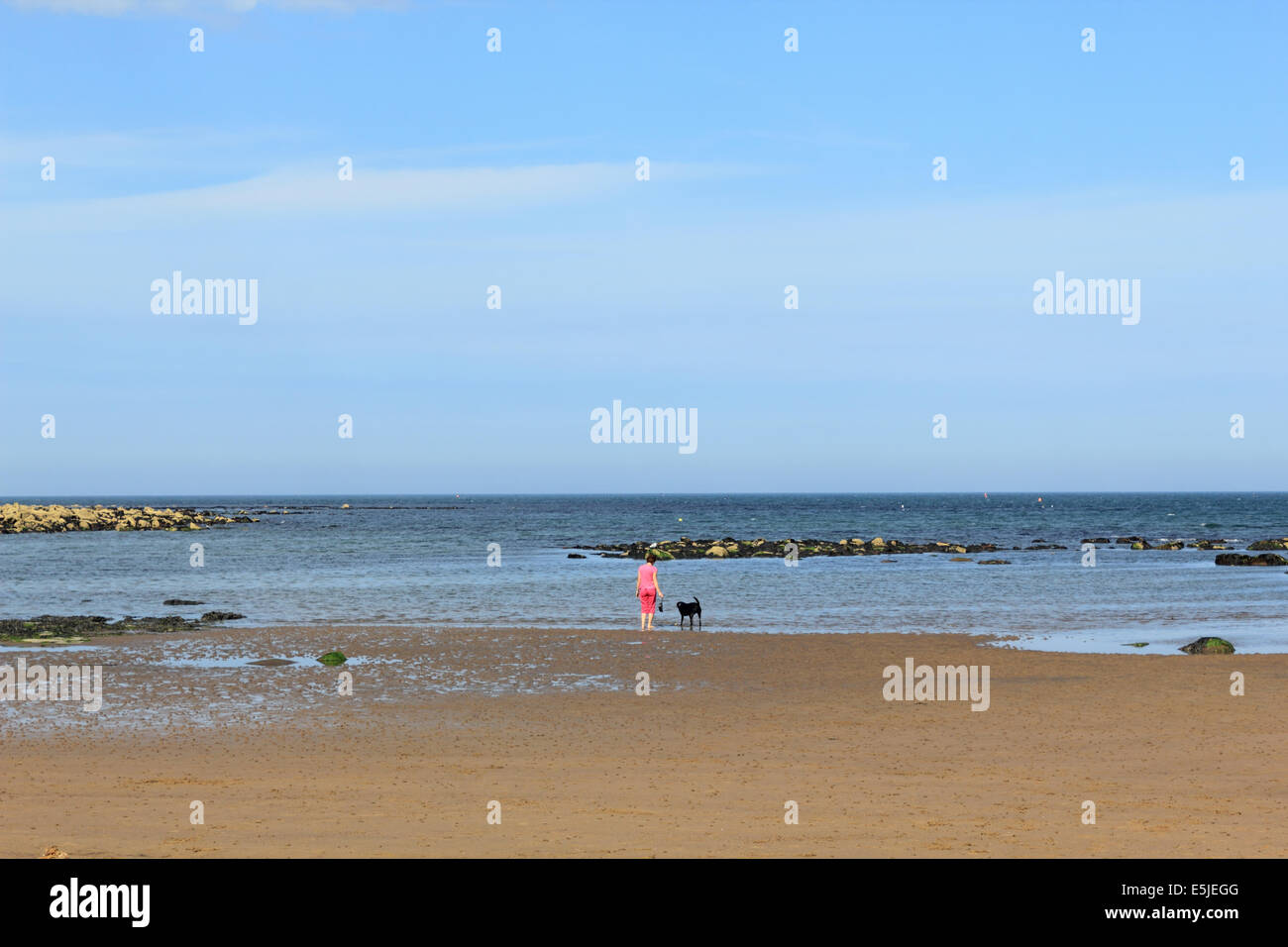 Frau geht Hund auf Runswick Bay, North Yorkshire, England, UK. Stockfoto