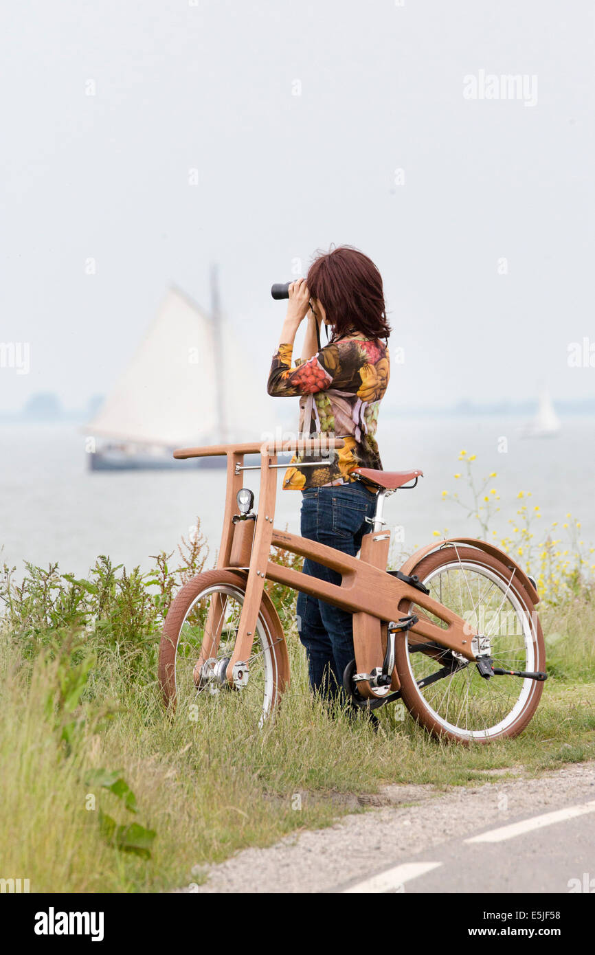 Niederlande, Venhuizen, Ast Bike. Das Dutch Design aus Holz-Bike. Frau Segelboot mit einem Fernglas betrachten Stockfoto