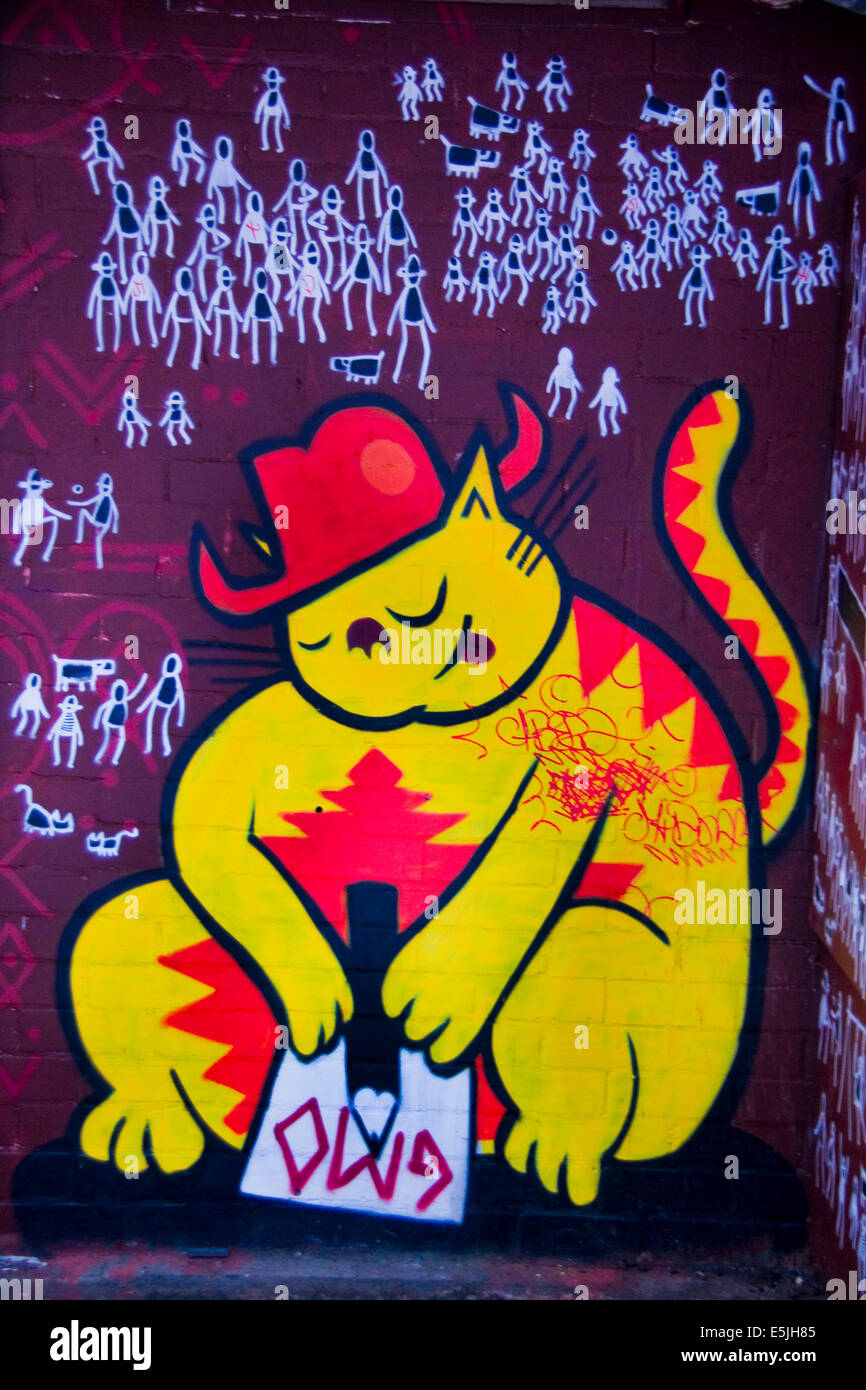 Bunte Graffiti in Seitengasse der Innenstadt, zeigt eine gelbe Katze mit einem roten Hut. Stockfoto