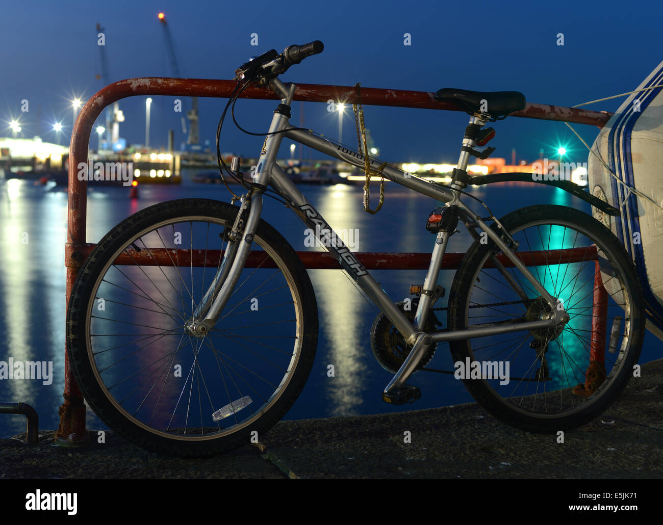 Fahrrad eingesperrt und angekettet an Geländer in einer Nacht Stockfoto