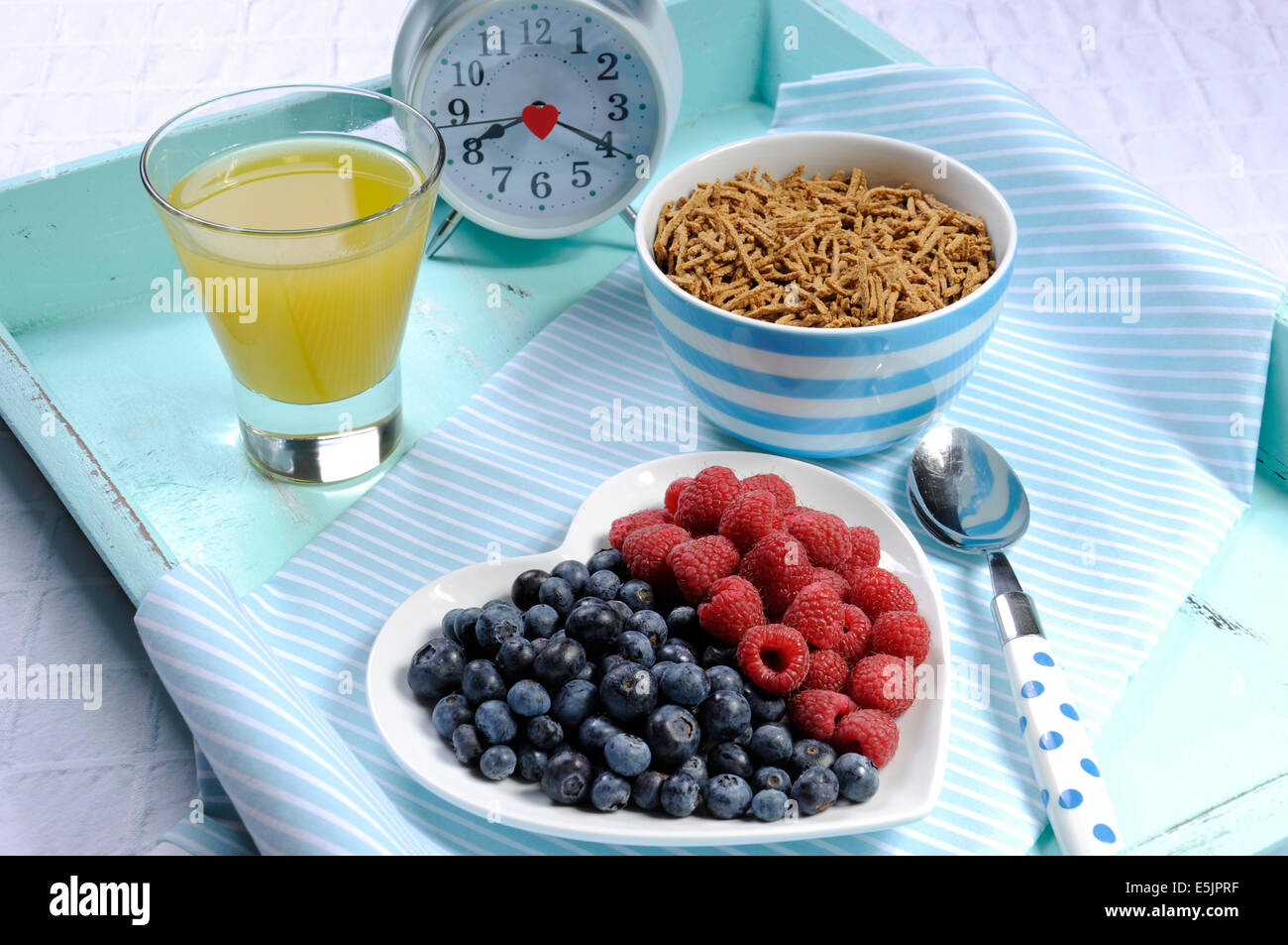 Gesunde Ernährung hohe Ballaststoffe Frühstück mit Schüssel Kleie Getreide und Beeren auf weißes Herz Teller auf Aqua blau Vintage Tablett Stockfoto