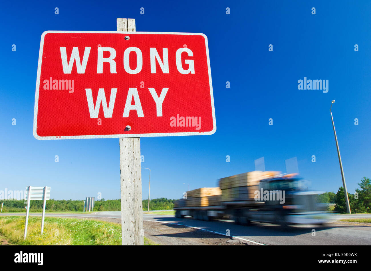 Ein roter Wrong Way Schild gegen ein klarer blauer Himmel mit einem LKW auf der Straße nähert sich Stockfoto