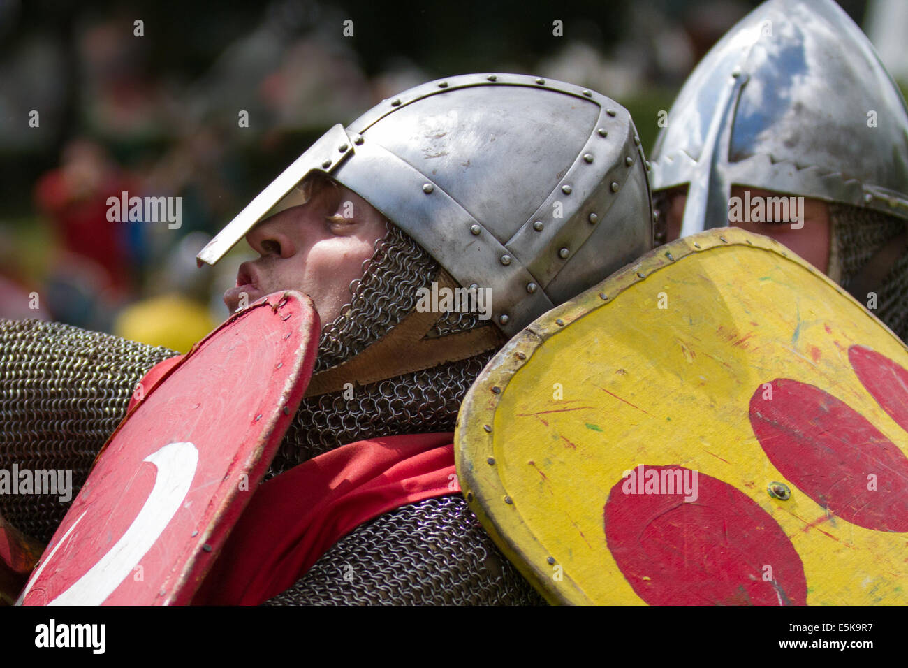 Beeston Castle, Cheshire, Großbritannien, 3. August 2014. Helmetrische bewaffnete Re-Enactors mit Schilden, beim Medieval Knights Tournament and Melee, einem Foot Soldier Combat Event. Historia Normannis, eine frühmittelalterlichen Kampfreenactment-Gruppe aus dem 12. Jahrhundert, erklärt die alte Kultur und Bräuche und stellt Ketten- und adrenalinbetriebene Reenactor Teams hochqualifizierter Ritter zur Verfügung, um mit Schwert-, Schild- und Vereinswaffen frontal zu kämpfen - eine Veranstaltung auf der English Heritage Site. Stockfoto