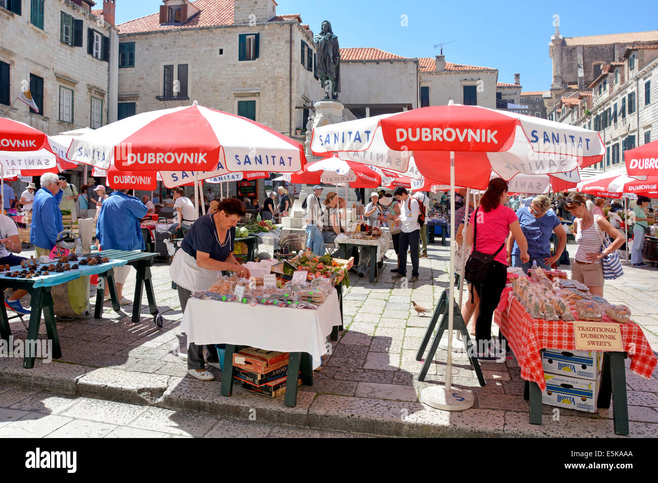 Stall und Sonnenschirme auf dem bunten historischen Marktplatz mit Stall Inhaber Touristen und Käufer Stadt Dubrovnik Kroatien Dalmatien Adria Europa Stockfoto